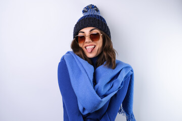 Young woman in a blue golf turtleneck, hat and scarf, sunglasses, on a white background, cheerful...