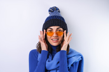 Young woman in a blue golf turtleneck, hat and scarf, sunglasses, on a white background, cheerful in a good mood