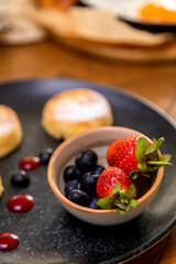 cheesecakes with berries on a plate garnished with jam. healthy breakfast.