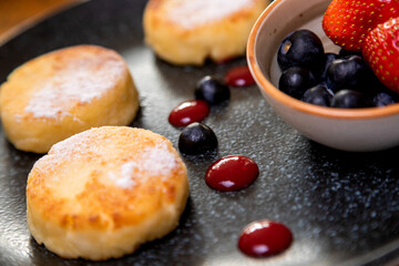 cheesecakes with berries on a plate garnished with jam. healthy breakfast.