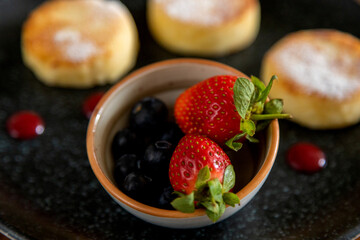 cheesecakes with berries on a plate garnished with jam. healthy breakfast.