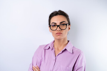 Young woman in a lilac shirt on a white background in glasses for vision looks angrily at the camera