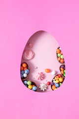 Chocolate easter eggs and decor flat lay for kids easter hunt egg concept on pink background. Sweets in the shape of an egg