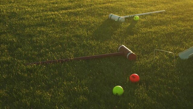 Croquet Mallet and balls laying on the grass or lawn at sunset golden hour