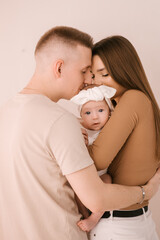 Stylish young family, photographed with a little beautiful baby. The family expresses love and awe to each other. Family and parenting concept.