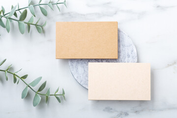 Business card mockup, kraft paper on marble with green leaf