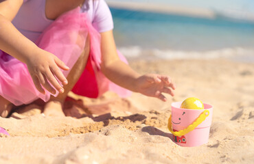 Kids hands on Easter egg hunt on the sandy beach. Happy Easter holidays concept 