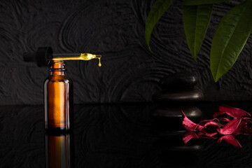 Amber glass bottles with dripping pipette, serum or herb extract. Black texture background, copy space, cosmetics background mock-up.