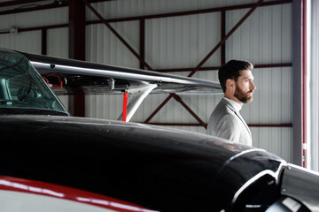 bearded businessman in suit looking away near helicopter on parking.