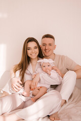 Stylish young family, photographed with a little beautiful baby. The family expresses love and awe to each other. Family and parenting concept.