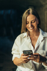 Beautiful young woman using smartphone while walking on the city streets on the coast during the night