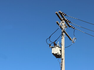 Transformer on the pole, transformer mounted on a pole for the trust to convert high voltage to low voltage. Blue sky background for copy space