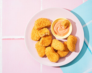 Vegetarian Nuggets with Vegan Dipping Sauce on apink pop art background with space for text, selective focus. Hard light, shadows, minimalism.