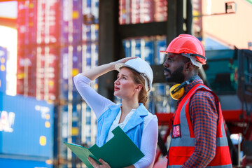 A team of African American men and Caucasian women wear helmets. Work on controlling the loading of containers from cargo ships