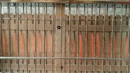 Close up of a vertical toaster. Only filaments can be seen. These are warming and start to get bright red. Parallel lines of metal in front of the burning filaments.