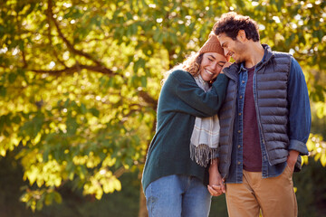 Happy Loving Couple Holding Hands Walking In Autumn Park Together