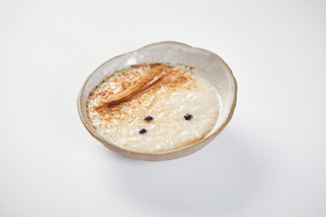 Arroz con leche with cinnamon, a typical Ecuadorian dessert served on a traditional plate on a white background. 