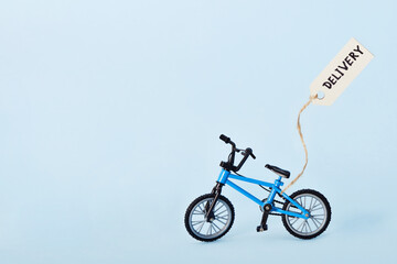 Creative eco delivery concept. Bicycle and tag with delivery text on blue background
