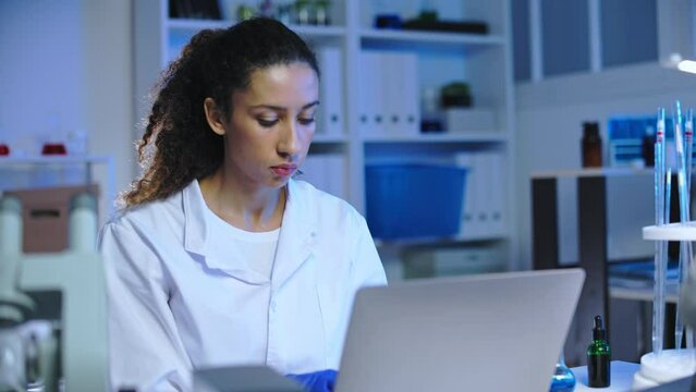 Female lab worker testing organic plant extract, developing anti-aging cosmetics