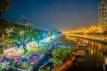 Fototapeta premium Springtime in Saigon, boat on canal, transport spring flower for Tet to Ben Binh Dong open air market, Vietnamese happy with Lunar New Year, Vietnam