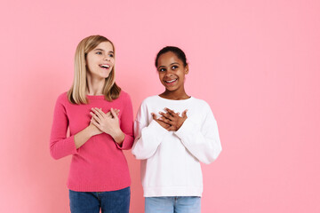 Multiracial two girls smiling while holding hands on their chests