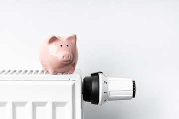 Sparschwein steht auf Heizkörper mit Thermostat