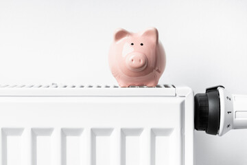 Sparschwein steht auf Heizkörper mit Thermostat - Close Up