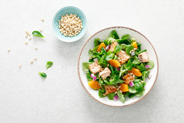 Salmon orange salad with pine nuts, red onion and corn salad. Top view