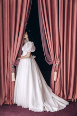 Bride in a white wedding dress in the ceremonial hall. Significant day. Burgundy background.
