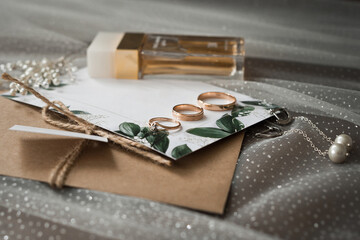 Wedding jewelry, perfumes and envelopes with invitations on the table