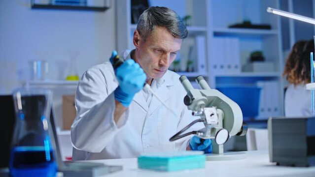 Laboratory technician examining virus cells under microscope vaccine development