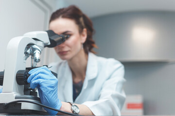 Woman scientist researching with microscope in laboratory