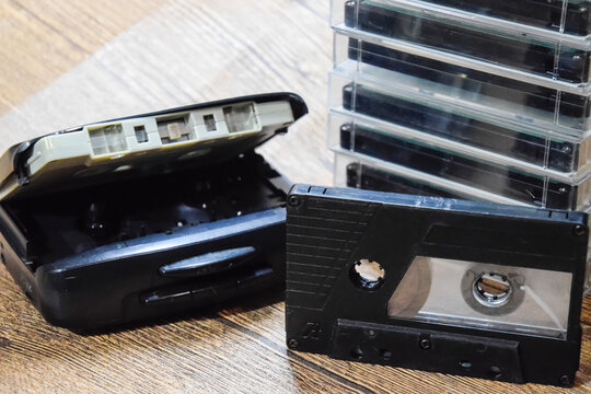 Retro audio cassettes next to a portable player to play compact cassettes.