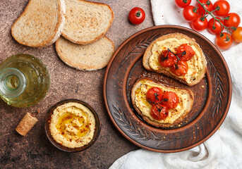 Healthy vegetarian sandwiches with whole grain bread, hummus, baked tomatoes and spices. bruschetta. A delicious snack for gourmets. Rustic style. Selective focus, top view - 487605102