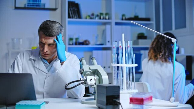 Confused forensic laboratory worker checking criminal care details on computer