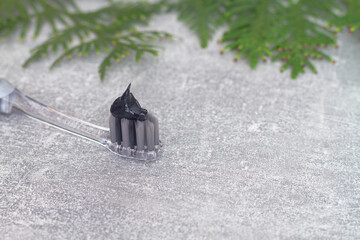 Toothbrush with silver antibacterial coating and black charcoal paste on a gray background with...