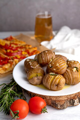 Blurred image of baked potatoes in a plate, rosemary, tomatoes, hot sandwiches on the table.