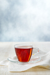 Glass cup of black tea on white wooden table