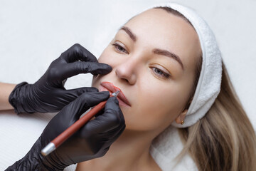 Young woman with permanent makeup on her lips in a cosmetologists salon. Permanent makeup tattoo....