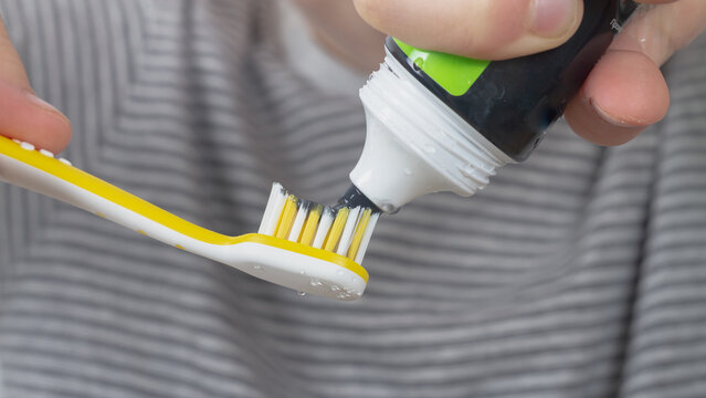 brushes his teeth with a black charcoal toothpaste