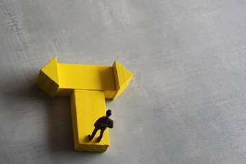 Decision making concept. Miniature man standing at a turning point. Copy space for text.