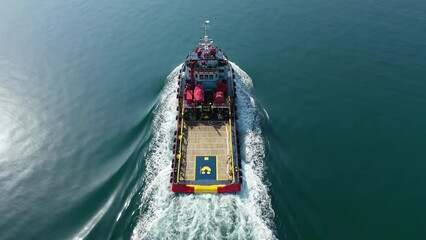 Aerial drone tracking video of tug boat cruising to guide large vessel to logistics port