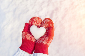 A snow heart in red mittens, a winter background on a background of light snow. Abstract postcard,...