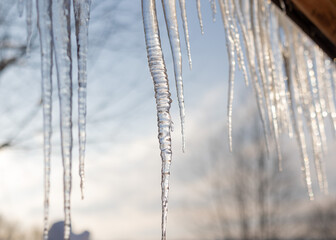 Close-up background of icicles. Icicles hanging from the roof. Cold winter weather, the concept of the winter season. Selective focus.