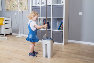 The assistant daughter helps around the house, the baby girl cleans the floors with a mop in the room