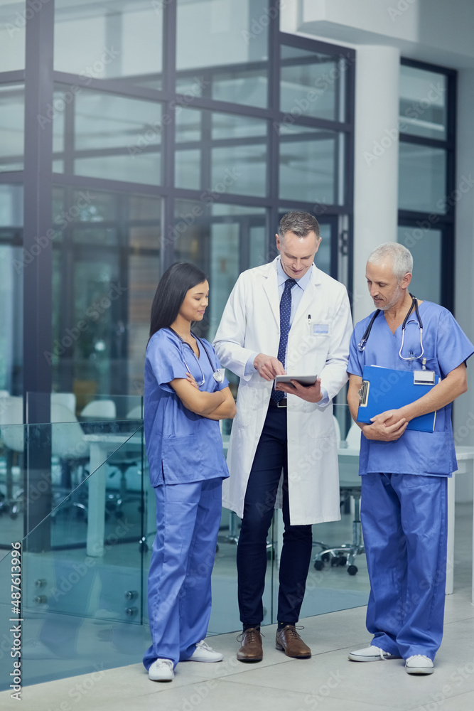 Poster comparing diagnosis. shot of a group of doctors talking together over a digital tablet while standin