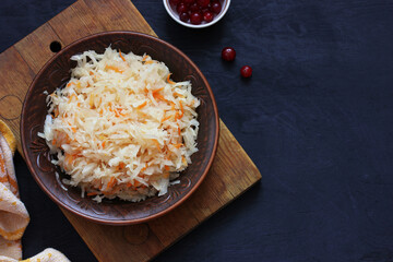 sauerkraut, homemade cabbage and carrot salad on a black background.