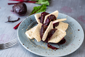 Tofu with baked red beetroot on plate, closeup.