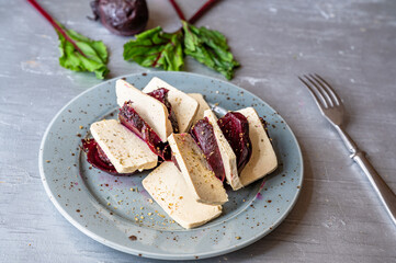 Tofu with baked red beetroot on plate.