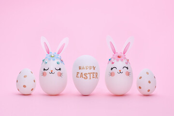 Easter composition of five different eggs on a pink background. White rabbit eggs and decorated...